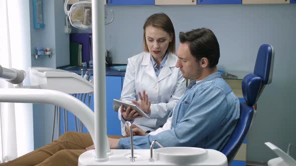 Dentist Showing Male Patient X-ray on Tablet