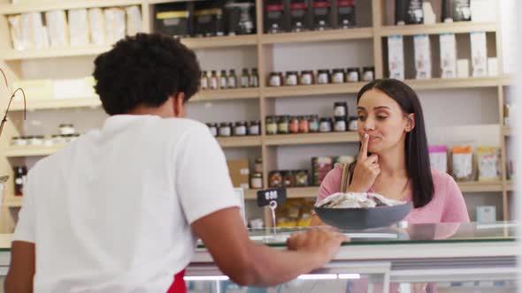 Animation of happy biracial woman trying diverse food at store