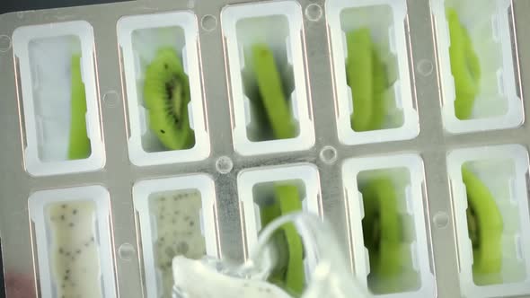 Making kiwi coconut chia popsicles in frozen ice pop maker.