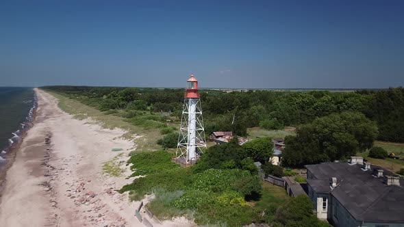 Beautiful aerial establishing view of white painted steel lighthouse with red top located in Pape, L