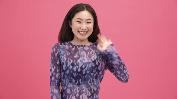 Pretty Asian woman waving at the camera