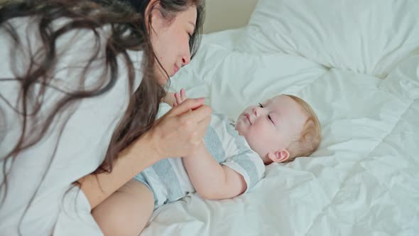 Happy family, Caucasian loving mom play with cute baby boy child on bed in bedroom at house.