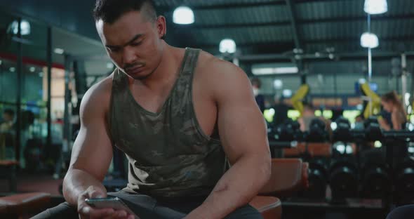 young man break sitting using smartphone after workout training exercise in fitness