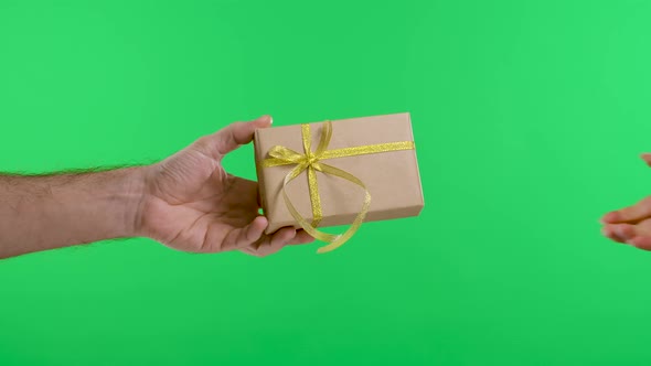 Male Hand Giving a Gift Box to a Female Hand on the Background of the Green Screen of the Chroma Key