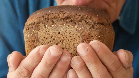 Making fragrant bread, bakery theme. close-up of an elderly man sniffing freshly baked bread while h