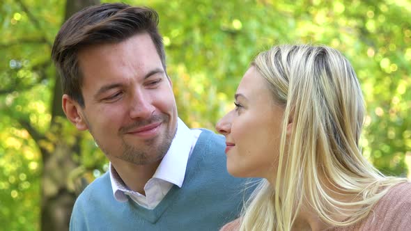 A Young Attractive Couple Smiles at the Camera in a Park on a Sunny Day - Closeup