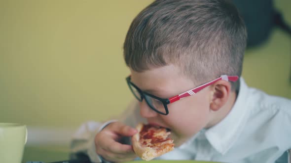 Pupil Eats Slice of Fresh Pizza at Cup on Table in Canteen