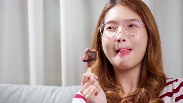 Asian young woman in glasses tasting chocolate ice cream