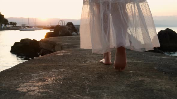 Closeup Female Feet Walking Along the Pier at the Sunset or Sunrise