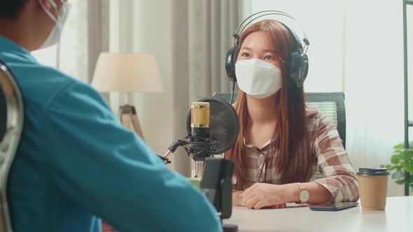 Asian Man Interview Young Female Guest Wearing Protect Mask In Podcast Studio