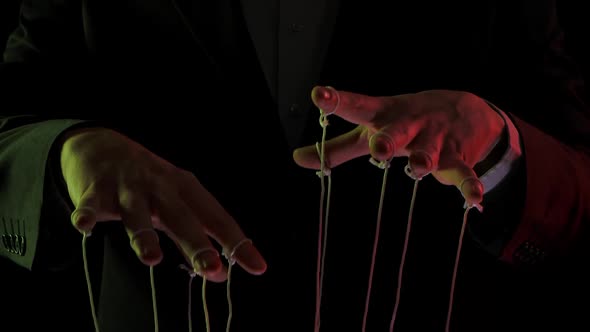 Businessman Leader in a Suit Manipulates the Strings of Puppets Tied To His Fingers