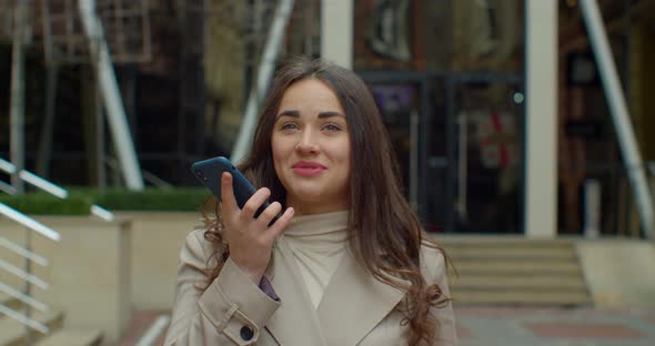 Woman Using a Smart Phone Voice Recognition Function Online Near Big Modern Office Building, Talking