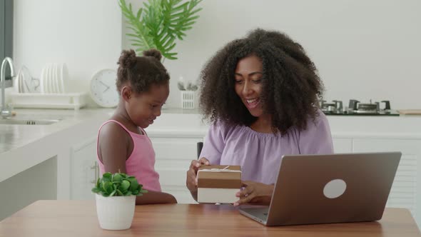 Charming Young Multiethnic Woman Rejoices While Receiving a Gift From Her Beloved Little Child Girl