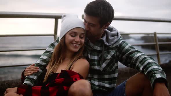 Loving Sport Couple Sitting on Border at Coastline Asphalt Road on Background Hills and Foggy Ocean