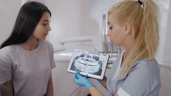 Dentist and Patient Choosing Treatment in a Consultation with Medical Equipment in the Background