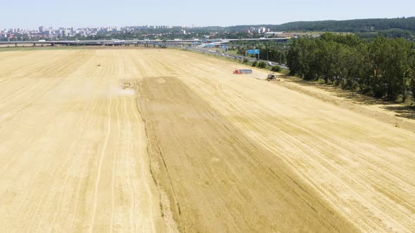 Aerial Drone Shot  Heavy Machinery (Combine Harvesters and a Truck) Work in a Field in a Rural Area