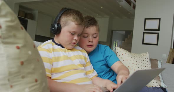 Caucasian boy with his brother sitting in living room and using laptop