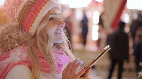 Woman in snowy night using digital tablet in winter city