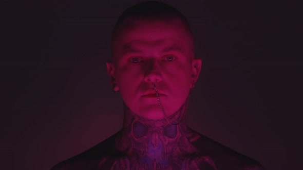 Tattooed Man with Nose Chain in Dark Studio