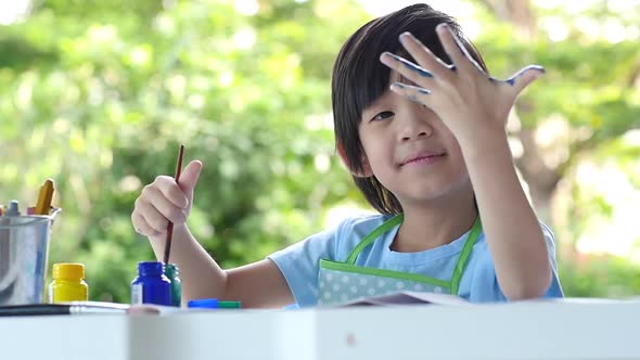 Cute Asian Child Enjoying Arts And Crafts Painting With His Hand