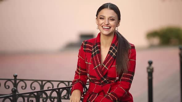 Happy Stylish Young Woman Is Sitting Outdoors