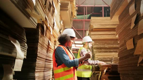 African American Female worker and colleague inspect paper storage warehouse.