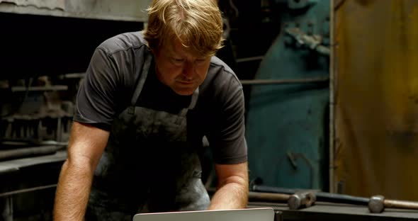 Blacksmith using laptop in workshop