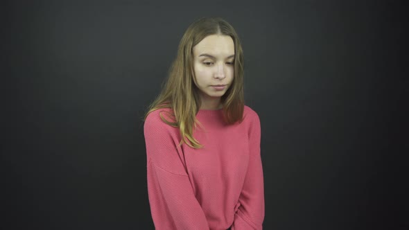 Shy Lady in Loose Pink Pullover Stands Under Electric Light