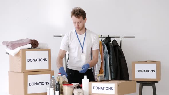 Young Volunteer Checking Clothes Donation Box and Making Notes Humanitarian Aid