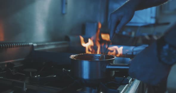 Hands of professional chef stirring meal