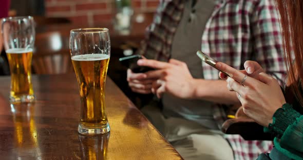 Man is Typing a Message on a Smartphone in a Bar While a Glass of