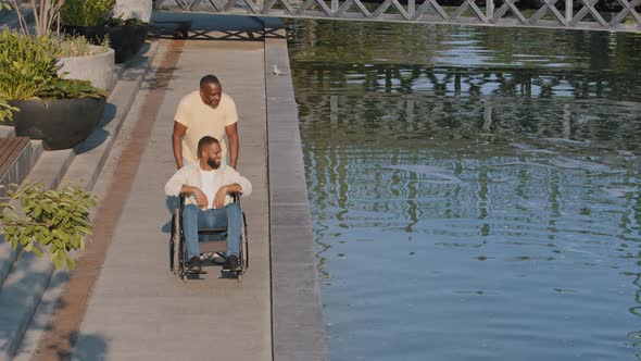 Two Black Men Friends or Relatives are Walking Together Along River on Summer Day