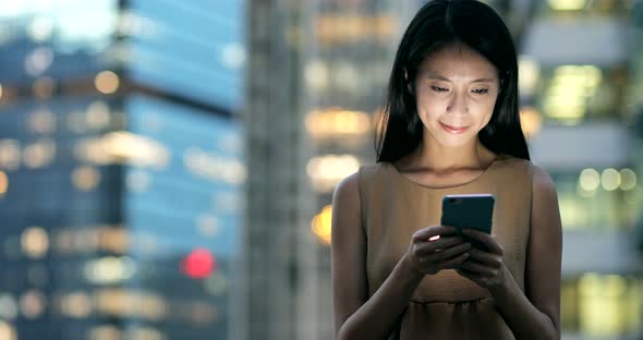 Businesswoman Looking at Mobile Phone in The City at Night 