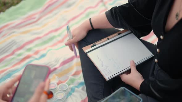 Close Up on Human Hands Holding a Notebook and a Smartphone