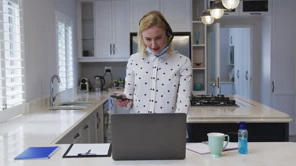 Woman with headset talking on smartphone at home