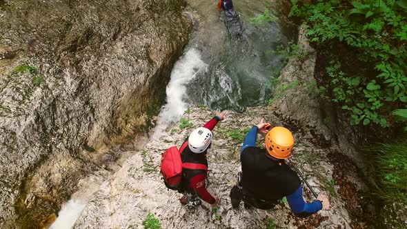 Aerial view of a group of people canyoning and jumping in the water on the river