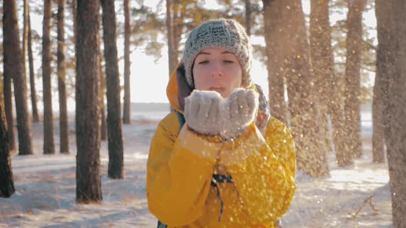 Beautiful Woman Blowing in the Snow in Pine Winter Forest