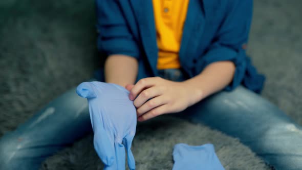 The boy puts on rubber gloves