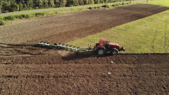 Modern Tractor with a Tillage Unit Prepares a Fertile Soil Dark Brown. The Farmer Plows the Land