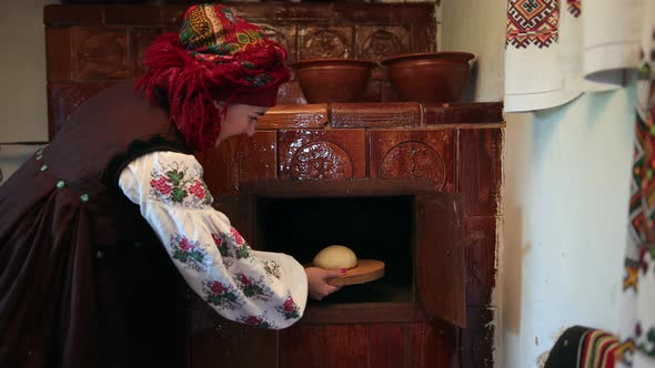 Young Woman in a Traditional Ukrainian Vyshyvanka Costume Puts Raw Bread Dough