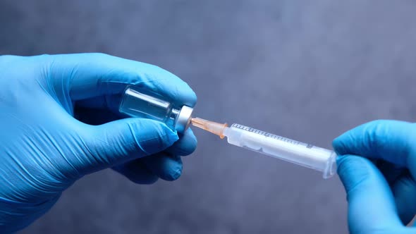 Doctor Hands in Medical Gloves Holds Syringe and Vaccine.
