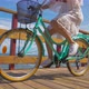 Pareja joven pasea en bicicleta por senda de madera junto al mar - VideoHive Item for Sale