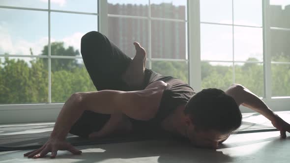 Wellness Man Doing Yoga in a White Room Filled with Light Man Does Stretching of Muscles Near the