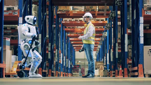 Worker Stops Warehouse Robot To Scan Barcodes on Boxes