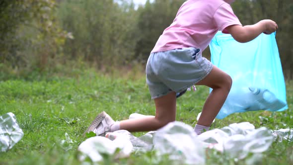 a Little Girl Removes Plastic Garbage and Puts It in a Biodegradable Garbage Bag Outdoors