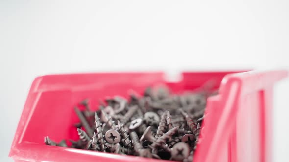 Red Plastic Container with Black Short Screws Swirling Close Up