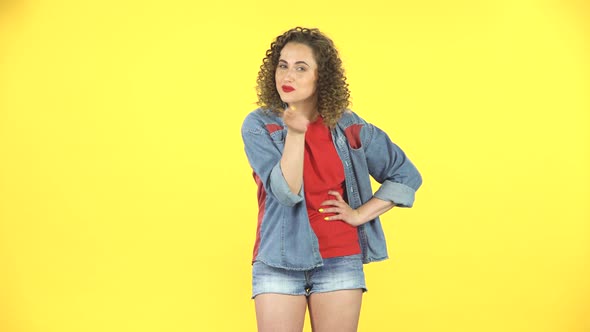 Girl Listens Carefully, Threatens with a Finger and Waves Her Head Negatively on Yellow Background