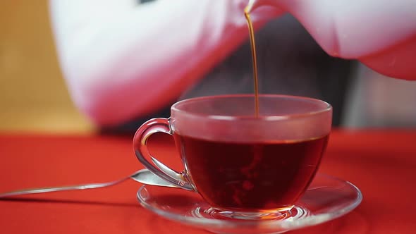 Relaxing Evening at Home. Woman Pouring Tea in a Cup. Hot and Tasty Beverage