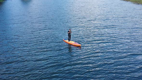 Aerial drone view of man is paddling on stand up paddleboarding in the mountain lakes