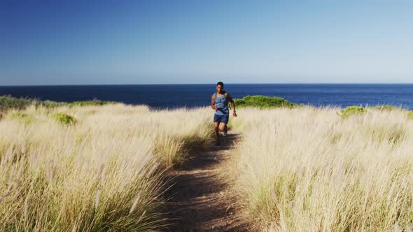 African american man cross country running in countryside on a coast